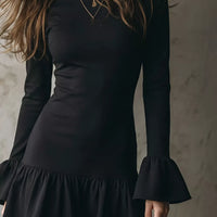 Black long-sleeve mini dress with ruffle hem and flared bell cuffs, close-up