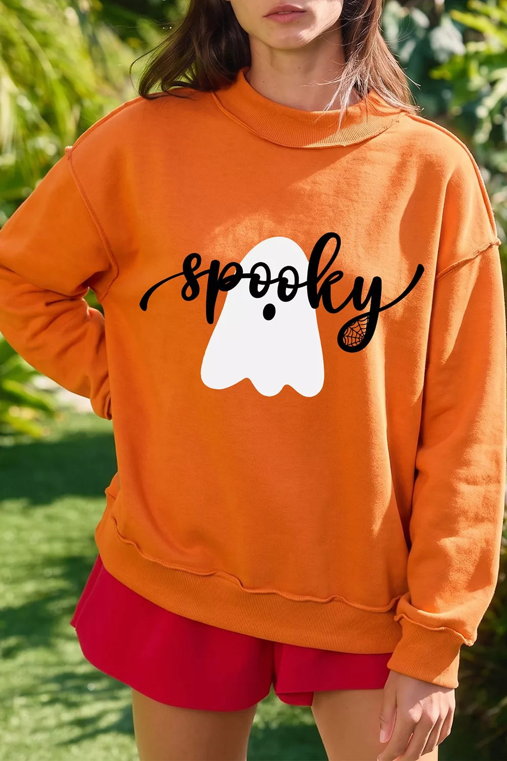 Orange mock neck sweatshirt with ghost graphic and black script print