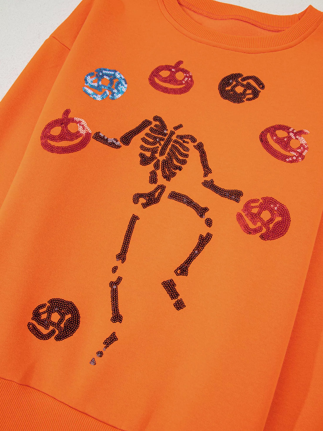 Orange crewneck sweatshirt with multicolor sequin Halloween critter and skeleton graphic