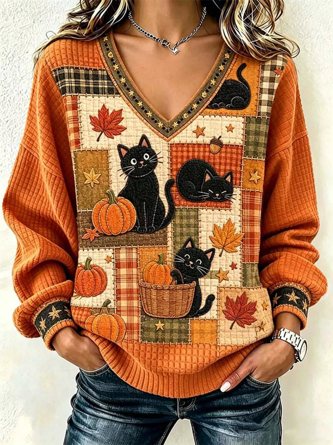 Orange V-neck sweater with black cats, pumpkins, and fall leaf patchwork front