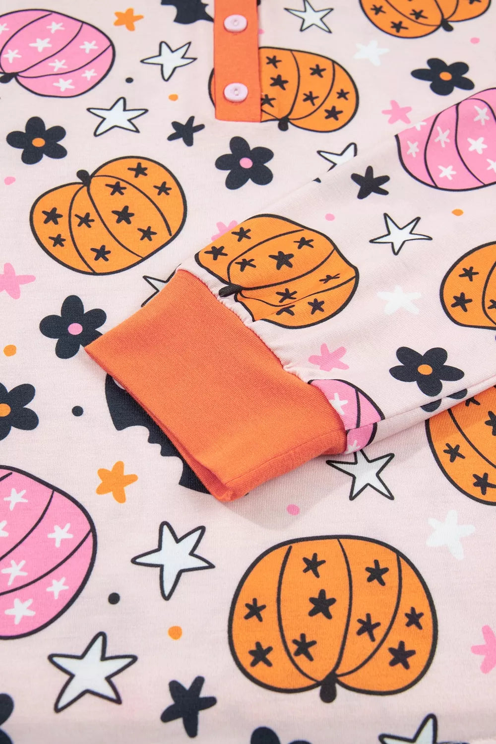Close-up: dusty pink pumpkin-print fabric with orange-trim collar detail