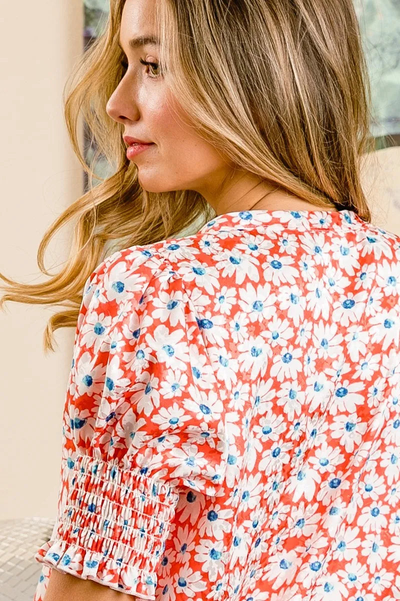 Orange floral V-neck top back view with smocked puff sleeves, blue-and-white print