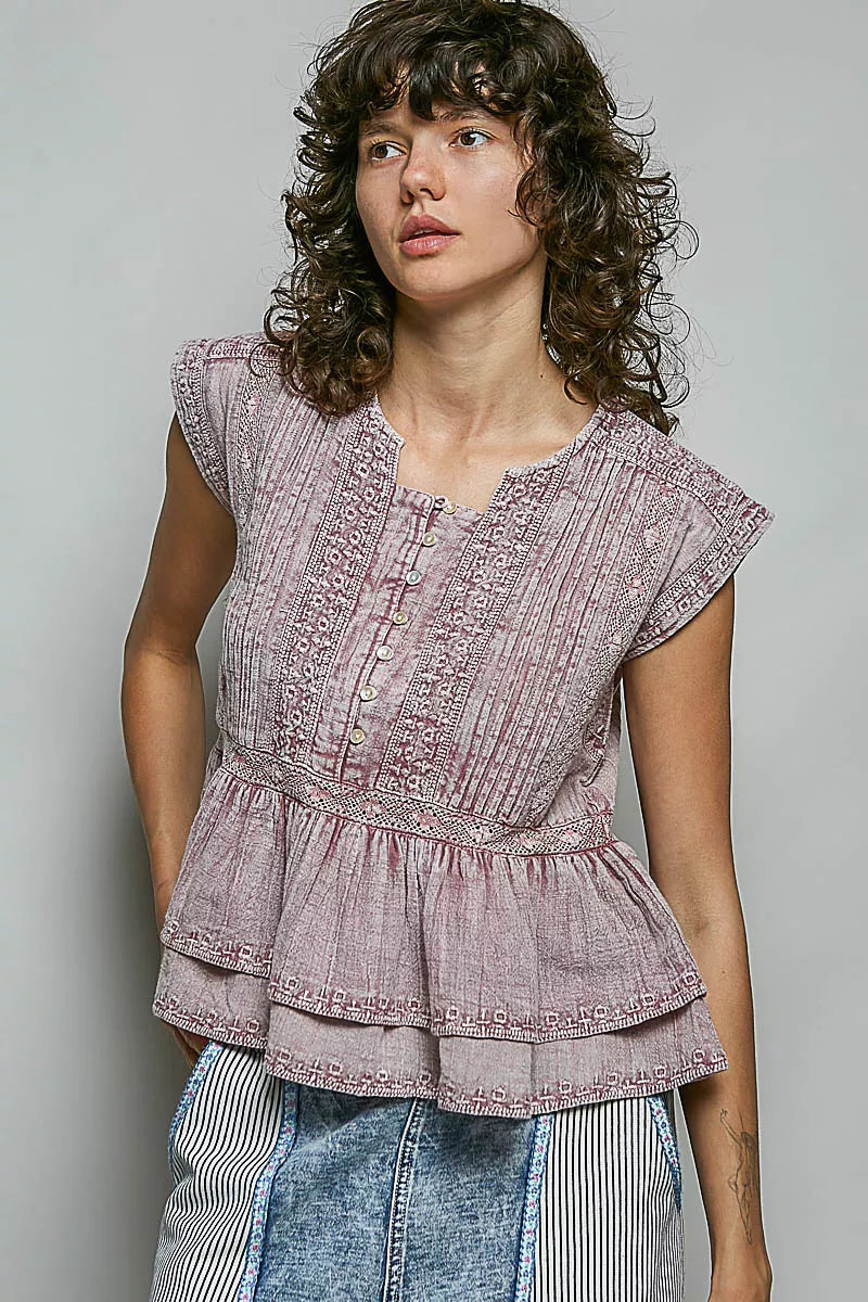 Pink sleeveless embroidered peplum blouse with ruffle hem and button placket.