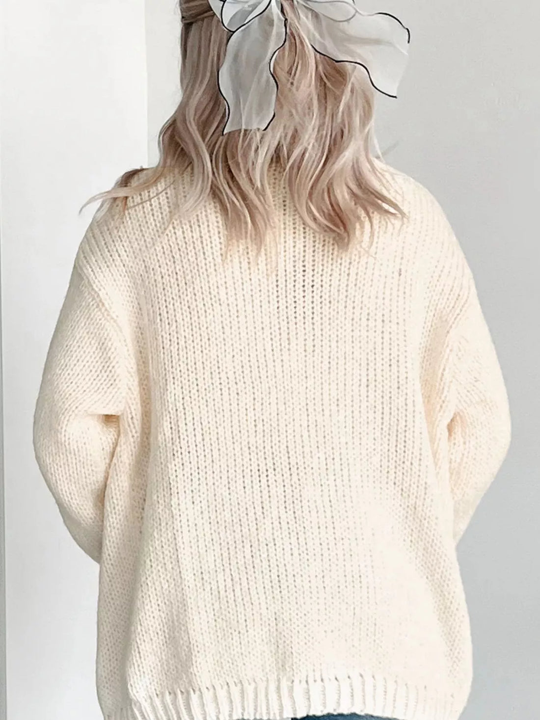 Off-white knit cardigan sweater with crew neck and full buttonless front.