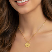 Gold-tone round pendant necklace worn by model, close-up