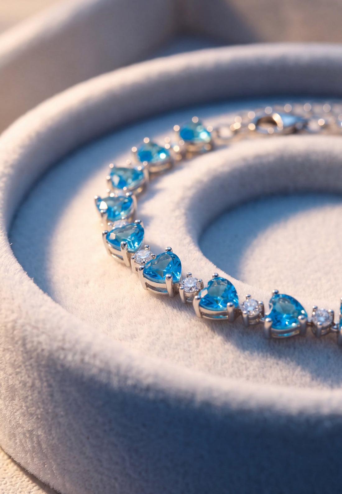 Close-up of silver tennis bracelet with heart-cut blue topaz stones