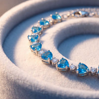 Close-up of silver tennis bracelet with heart-cut blue topaz stones
