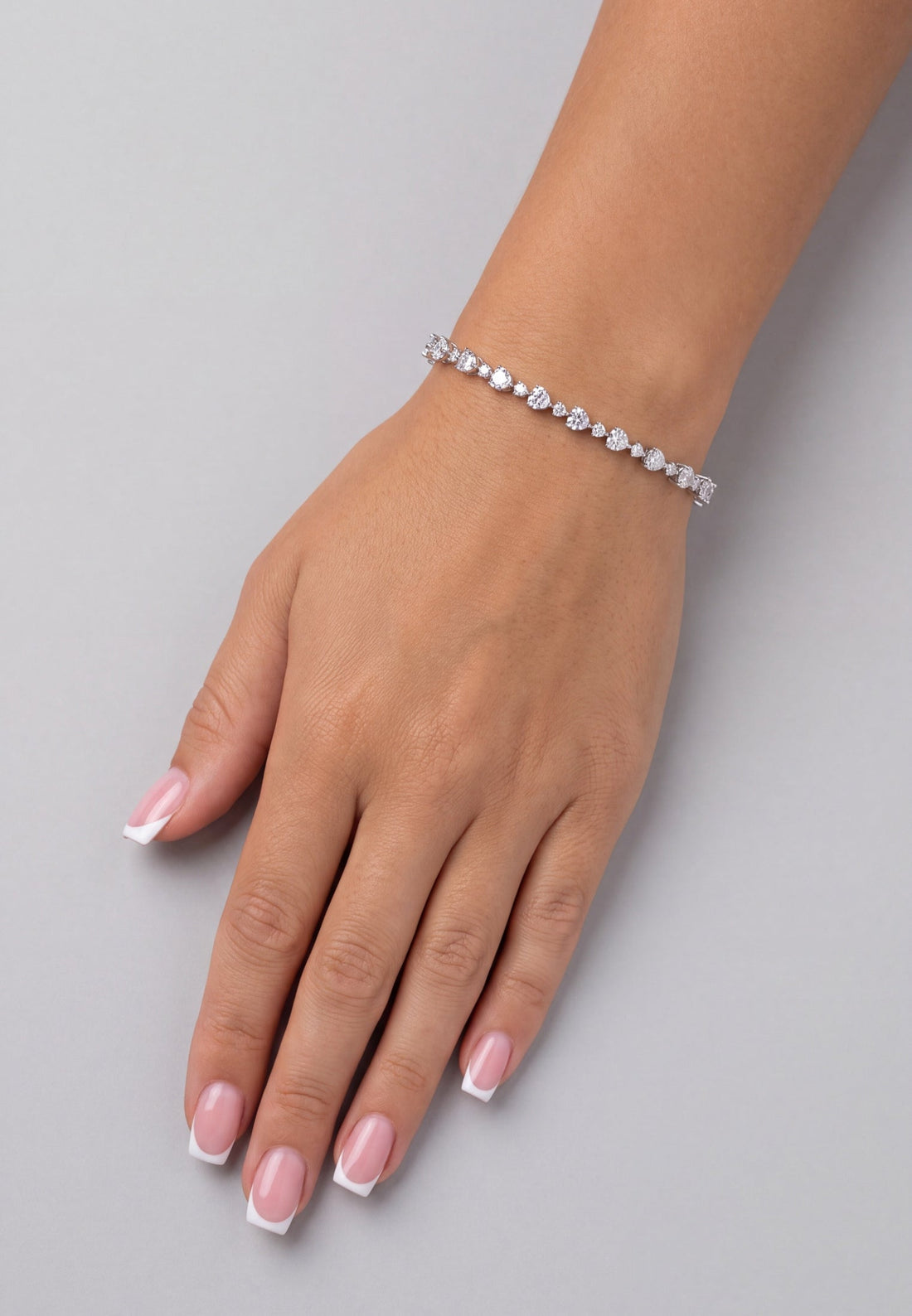 Tennis bracelet with oval stones on wrist, chain links and clasp