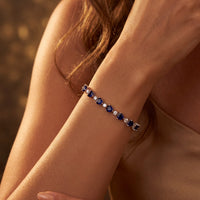 Silver tennis bracelet with blue heart gemstones worn on wrist