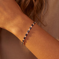 Gold-tone bracelet on wrist with blue faceted stones in repeating links