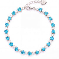 Silver tennis bracelet with heart-cut blue topaz stones and oval clasp tag