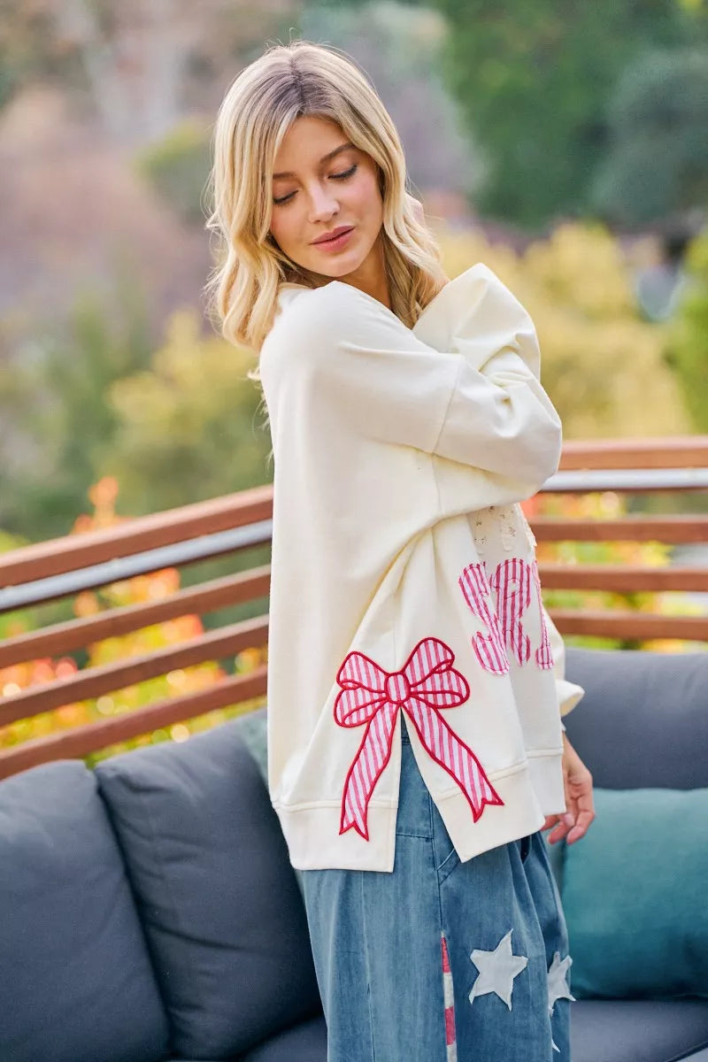 Cream sweatshirt with red bow patch and stars-and-stripes graphic