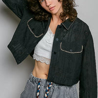 Black cropped eyelet cotton jacket with button placket, pointed collar, and stitched flap pockets.