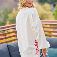 Cream sweatshirt back view with red bow graphic and blue bow patch on the sleeve.