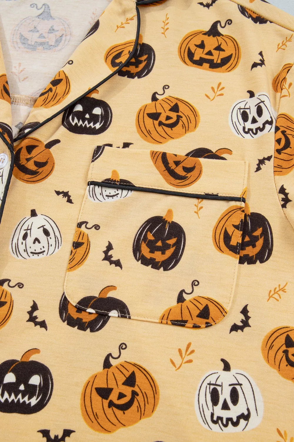 Gold Halloween-print long-sleeve top close-up, sleeve cuff and button placket