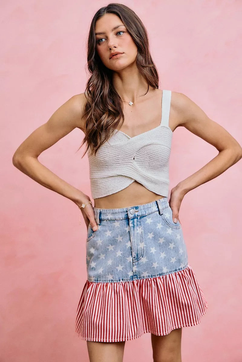 Blue denim mini skirt with star print top section and red-and-white striped ruffled hem.