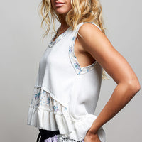 Off-white ribbed tank top with floral patch detail and layered ruffle hem