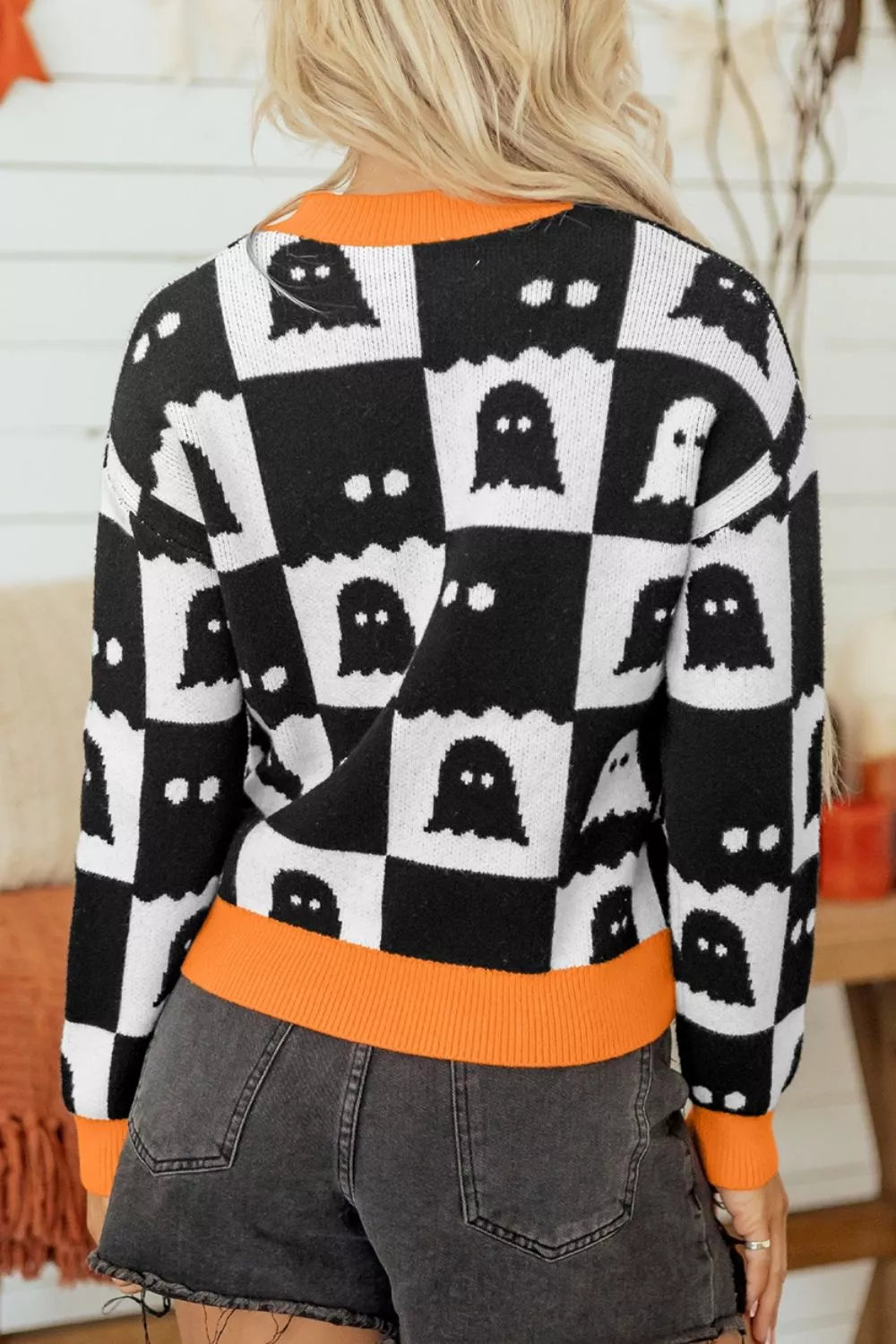 Back view of black and white ghost checkerboard sweater with orange ribbed collar