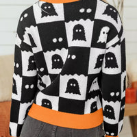 Back view of black and white ghost checkerboard sweater with orange ribbed collar