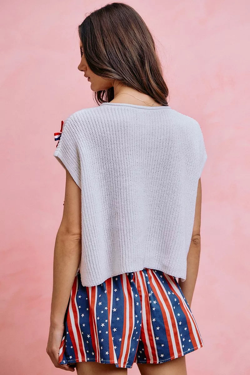 Off-white dolman sweater top from the back view, showing knit texture and bow trim