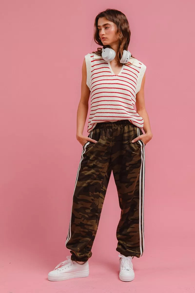 Camouflage track pants with long white side stripe and jogger-style tapered silhouette.