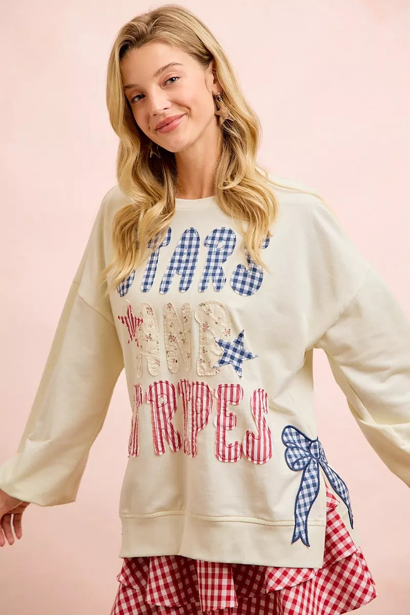 Cream sweatshirt with blue star top, red stripe lettering, and bow patch on right side.