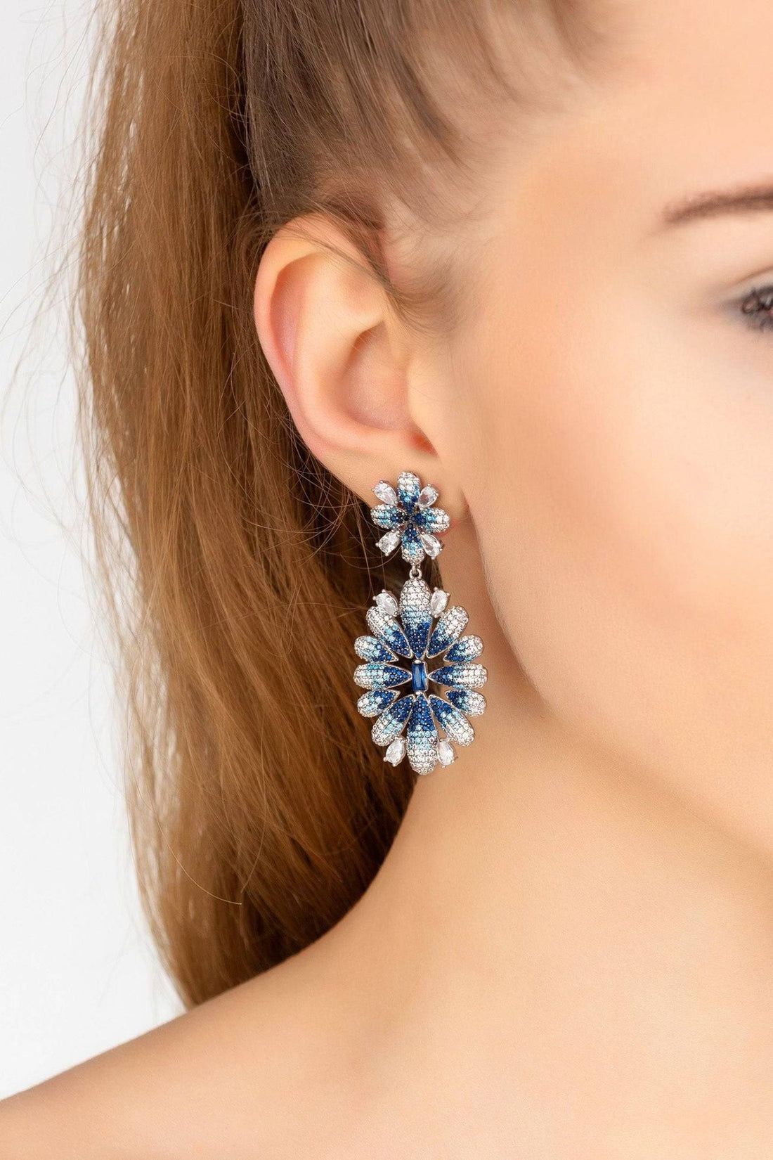 Silver-tone crystal flower drop earrings with ice blue gradient, shown on ear
