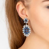 Silver-tone crystal flower drop earrings with ice blue gradient, shown on ear