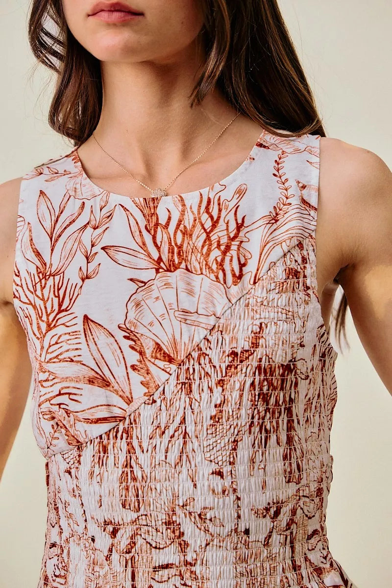Close-up of coral and white shell-print sleeveless dress with smocked bodice detail