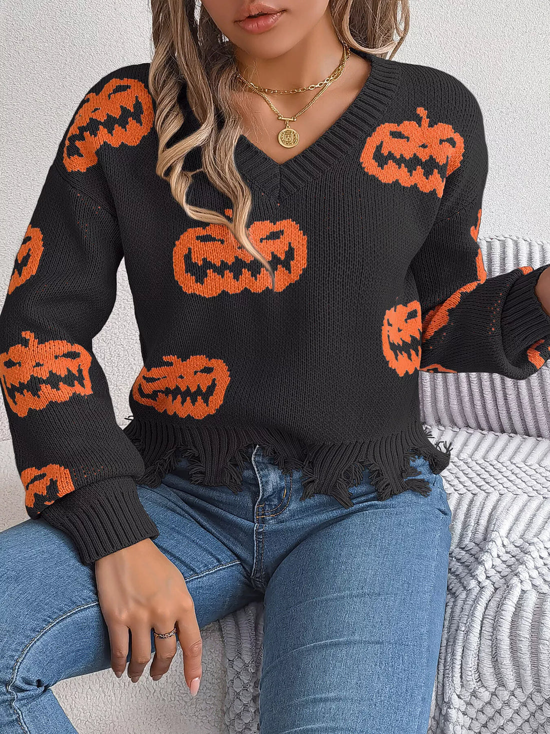 Black knit V-neck sweater with orange jack-o’-lantern pattern and frayed distressed hem