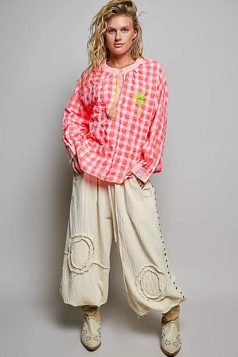Pink gingham embroidered blouse with long sleeves and palm tree front, paired with pants