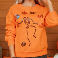 Orange crewneck sweatshirt with sequin skeleton and candy icons, ribbed hem and cuffs