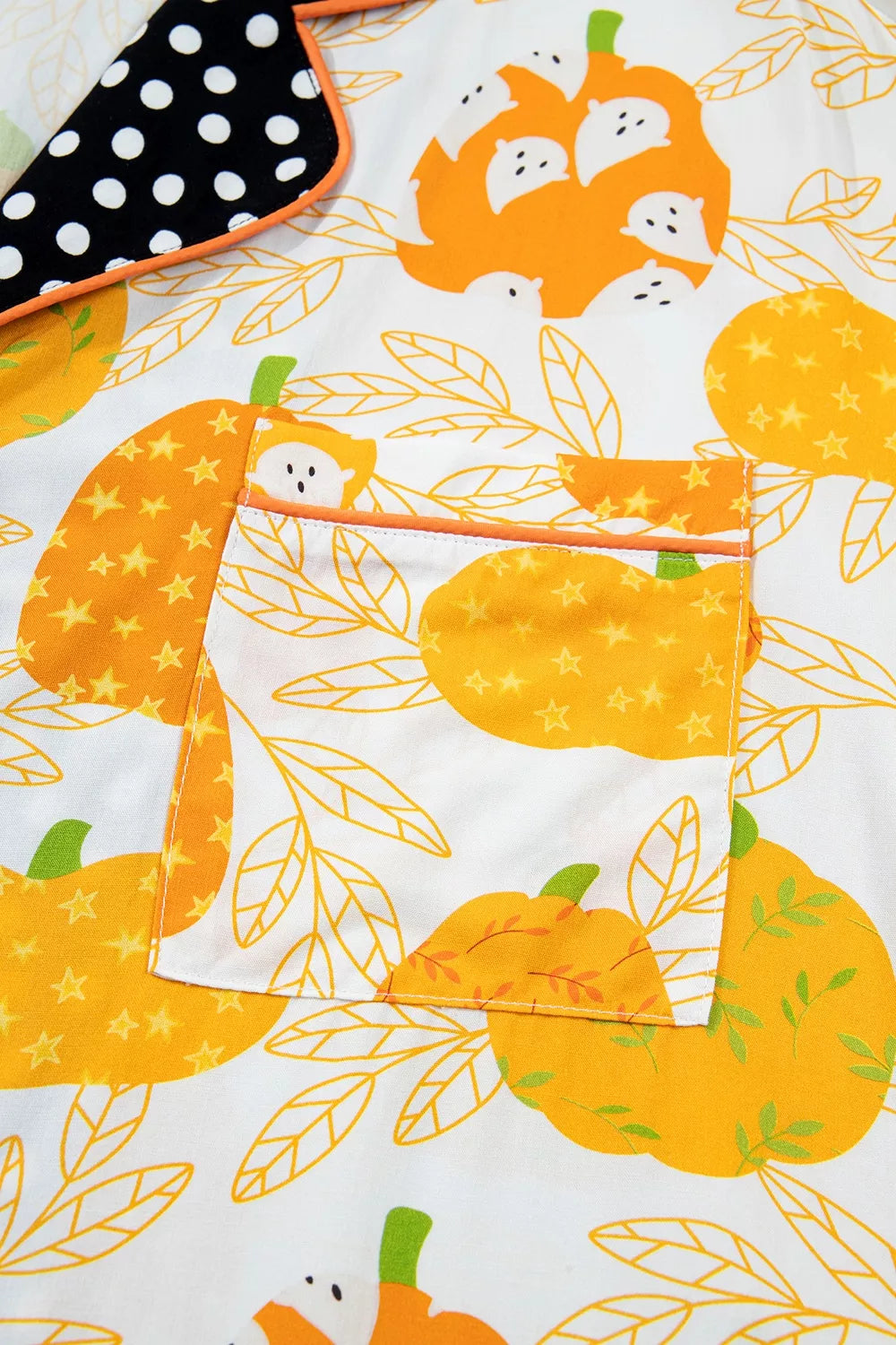 Close-up of orange and yellow pumpkin print on white pajama fabric with button placket