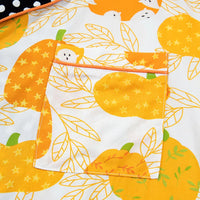 Close-up of orange and yellow pumpkin print on white pajama fabric with button placket