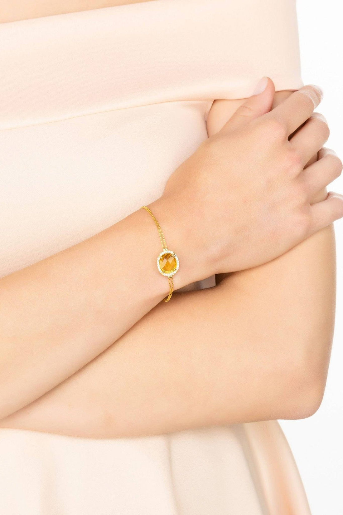 Gold citrine gemstone bracelet on wrist with oval center and crystal halo