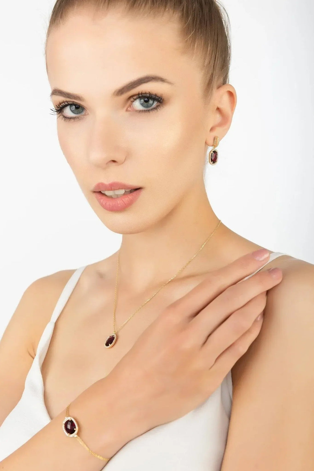 Gold chain bracelet with oval red gemstone bezel on model’s wrist