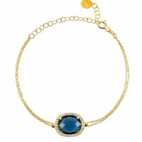 Gold chain bracelet with oval blue gemstone center