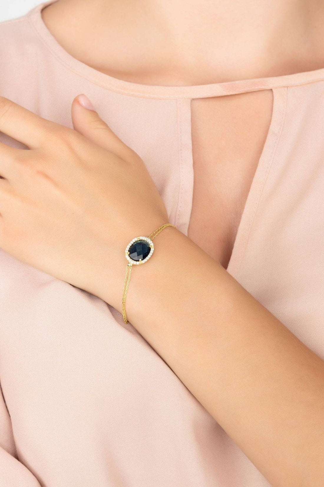 Gold oval blue gemstone bracelet shown on wrist