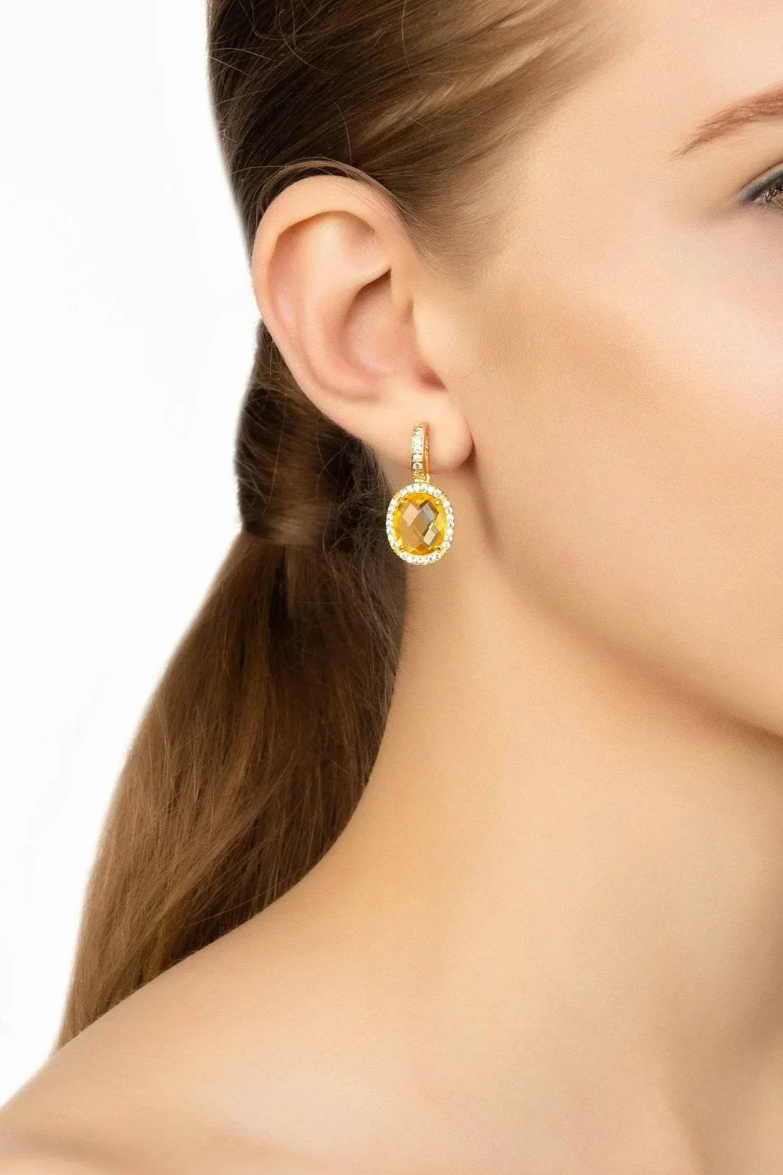 Gold citrine oval drop earrings with crystal halo, shown on ear