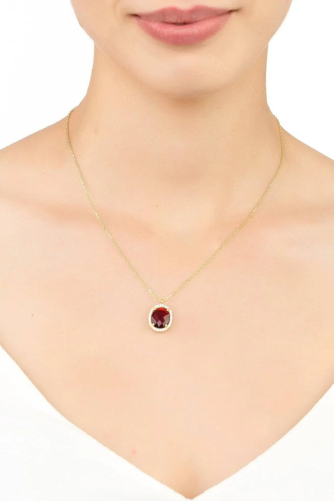 Gold chain necklace with small red oval garnet pendant and clear stone border