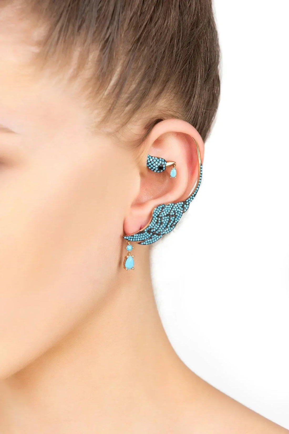 Turquoise bird ear climber earring on right ear, gold-tone hook with crystal details