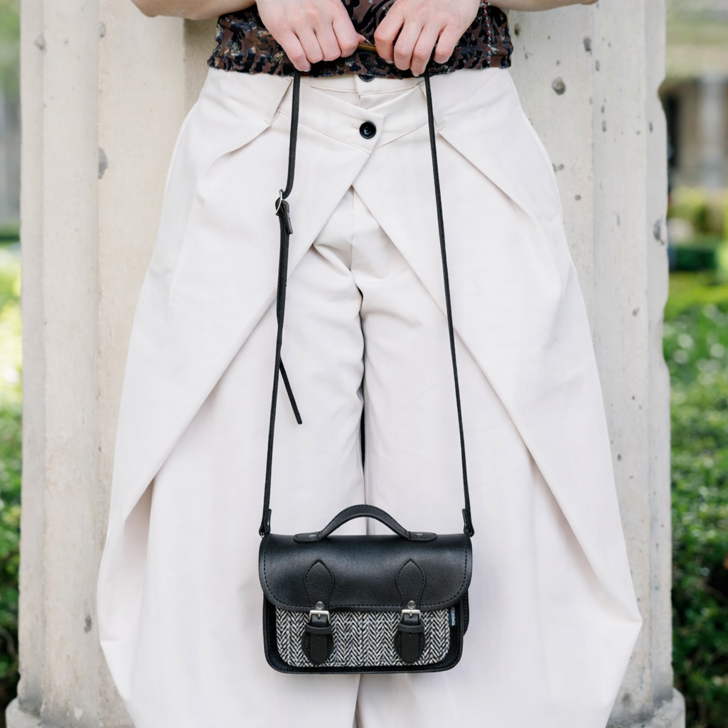 Black leather micro satchel with adjustable crossbody strap, tweed front panel and buckle flap