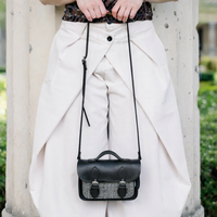 Black leather micro satchel with adjustable crossbody strap, tweed front panel and buckle flap