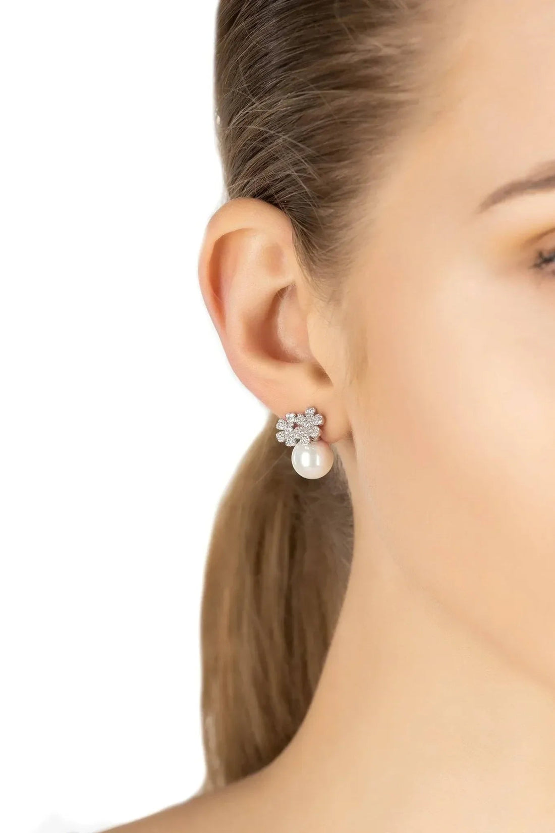 Silver flower stud earrings with pearl drops, worn on ear