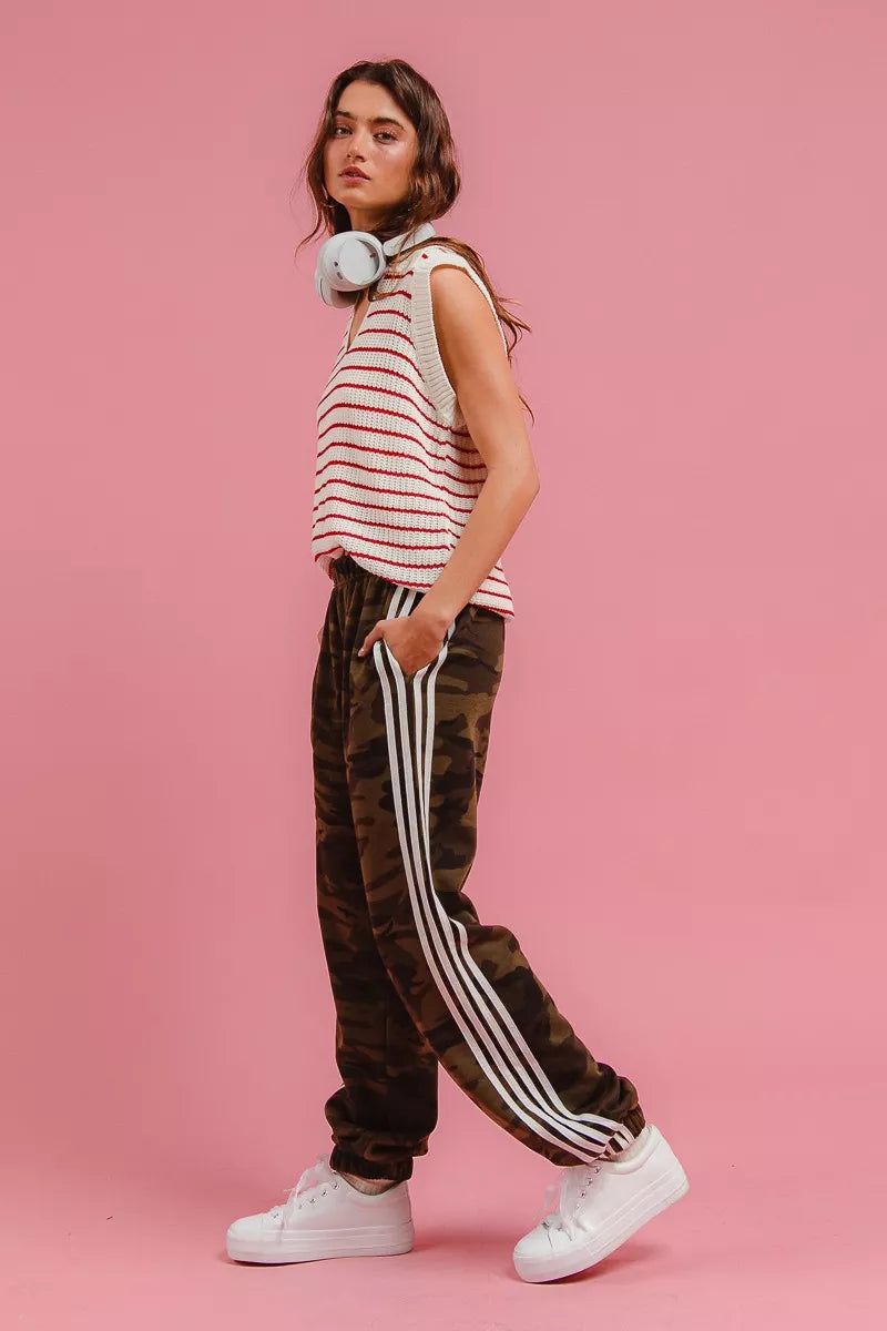 Camouflage track pants with white stripe along the leg and tapered cuffed hems.