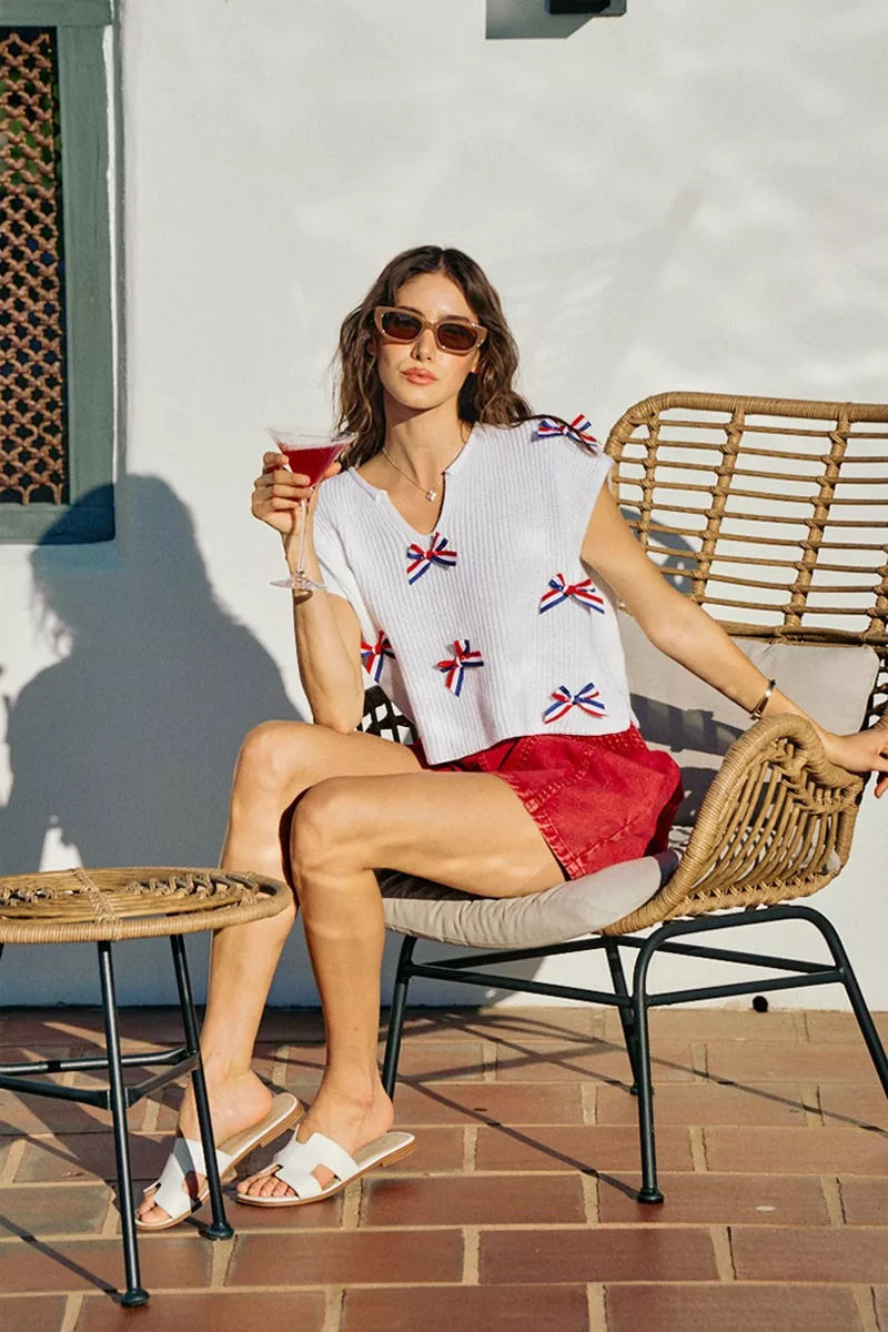 Off-white dolman sweater with scattered red-white-blue ribbon bow trim