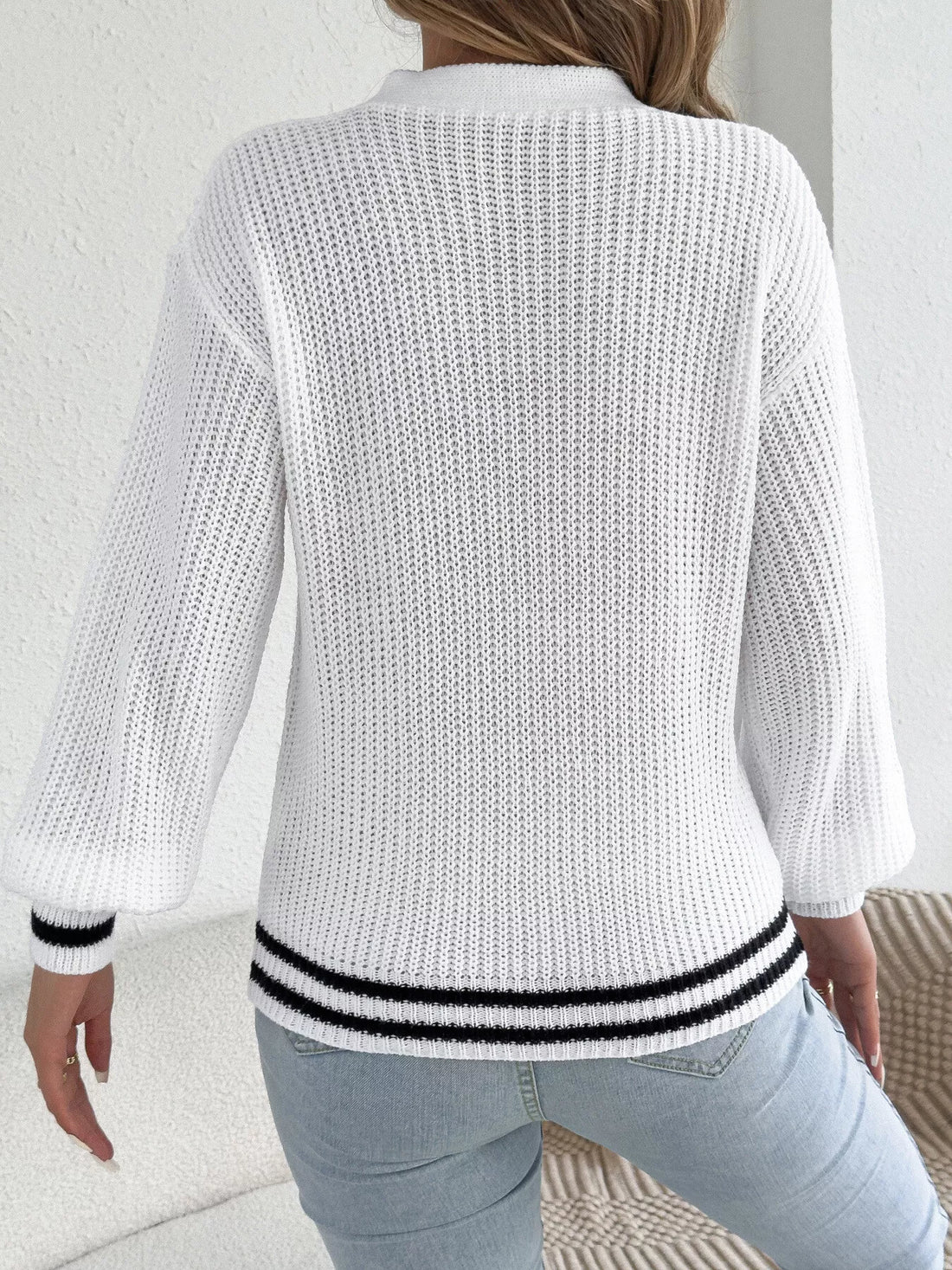 White cutout cable knit sweater, back view with ribbed hem and cuffs in black trim