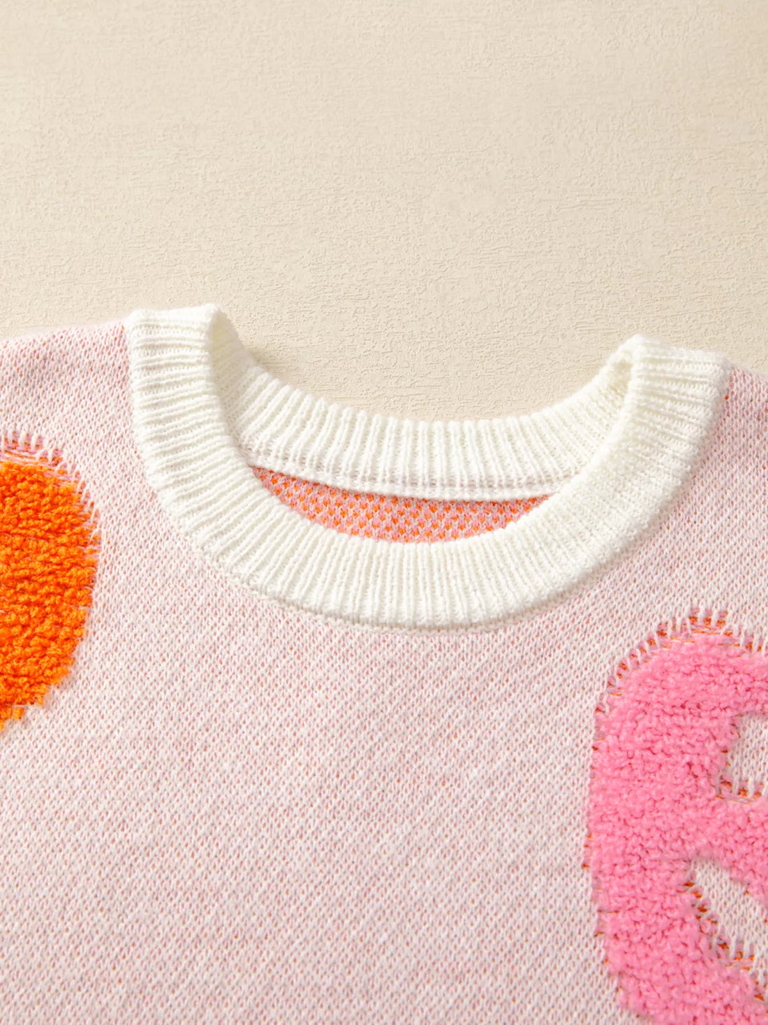 Dusty pink crewneck sweater with ribbed collar and orange pumpkin and pink ghost motifs