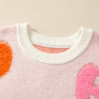 Dusty pink crewneck sweater with ribbed collar and orange pumpkin and pink ghost motifs