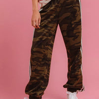 Camouflage track pants with white side stripes and elastic ankle cuffs.